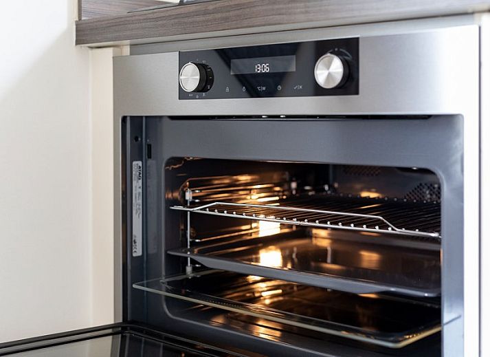 Gemuetlicher Aussenbereich des Ferienhauses Duinroos, Ballum, Ameland, mit Terrassenmoebeln unter einem Sonnenschirm.