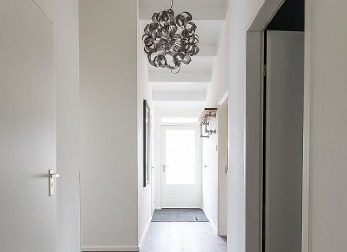 Gemuetlicher Aussenbereich des Ferienhauses Duinroos, Ballum, Ameland, mit Terrassenmoebeln unter einem Sonnenschirm.