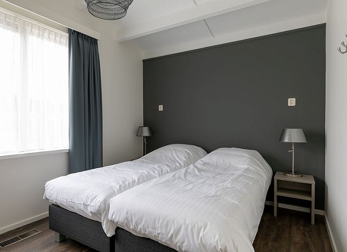 Gemuetlicher Aussenbereich des Ferienhauses Duinroos, Ballum, Ameland, mit Terrassenmoebeln unter einem Sonnenschirm.