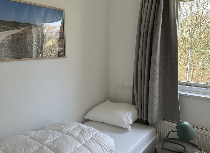 Houten eettafel op het terras van Zeevonk vakantiehuis in Ballum, Ameland, met uitzicht op de groene omgeving.