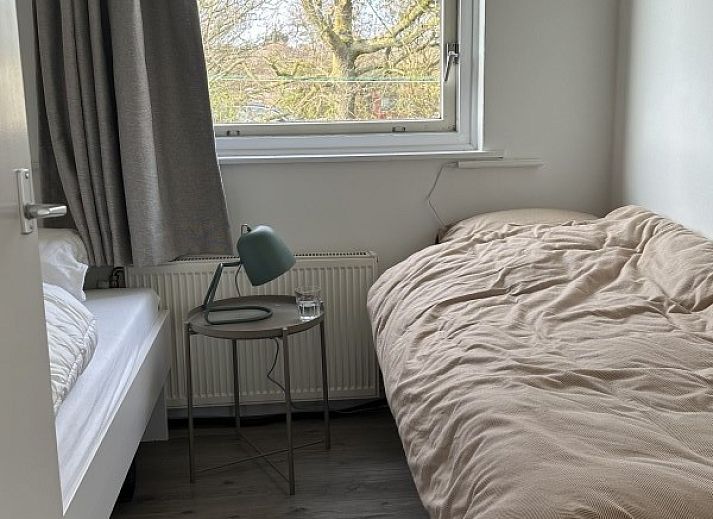 Houten eettafel op het terras van Zeevonk vakantiehuis in Ballum, Ameland, met uitzicht op de groene omgeving.