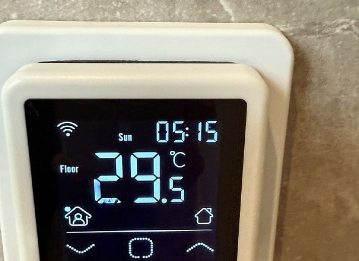 Houten eettafel op het terras van Zeevonk vakantiehuis in Ballum, Ameland, met uitzicht op de groene omgeving.