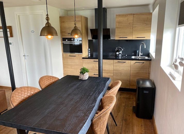 Stijlvolle woonkamer in Appartement Fleurie, Ballum, Ameland met comfortabele leren banken en houten vloeren.