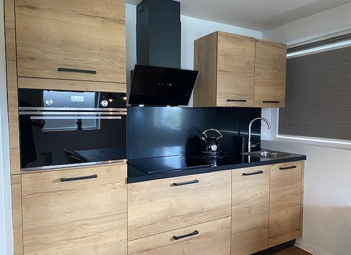 Stijlvolle woonkamer in Appartement Fleurie, Ballum, Ameland met comfortabele leren banken en houten vloeren.