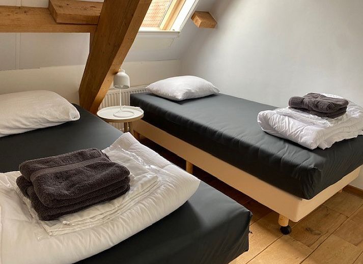 Stijlvolle woonkamer in Appartement Fleurie, Ballum, Ameland met comfortabele leren banken en houten vloeren.