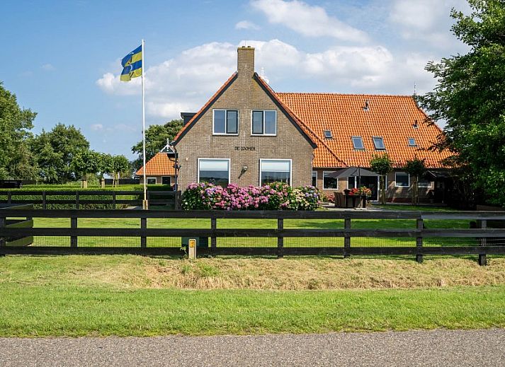 Moderne eetkamer en keuken in Appartement Fleurie, Ballum, Ameland met houten meubels en sfeervolle verlichting.