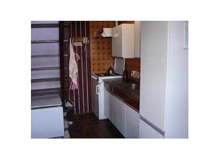 Vacation home Suzan in Ballum, Ameland with charming facade and red gate, surrounded by nature on the Wadden Islands.