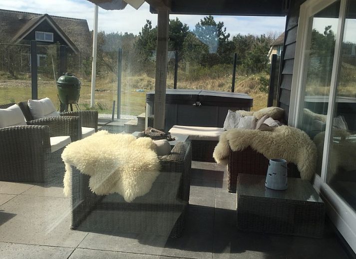 Ruim terras van Wellnessvilla Zee & Zo in Buren, Ameland omgeven door bloemen en grasland.