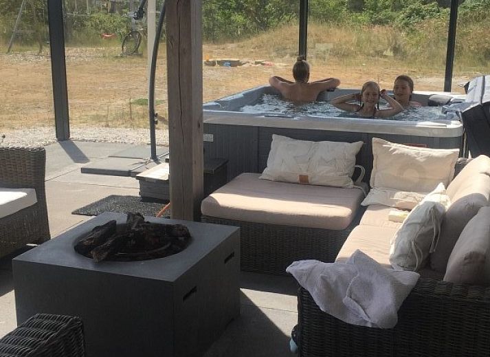 Ruim terras van Wellnessvilla Zee & Zo in Buren, Ameland omgeven door bloemen en grasland.