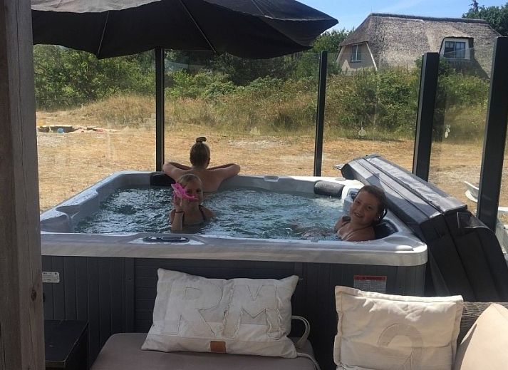 Ruim terras van Wellnessvilla Zee & Zo in Buren, Ameland omgeven door bloemen en grasland.