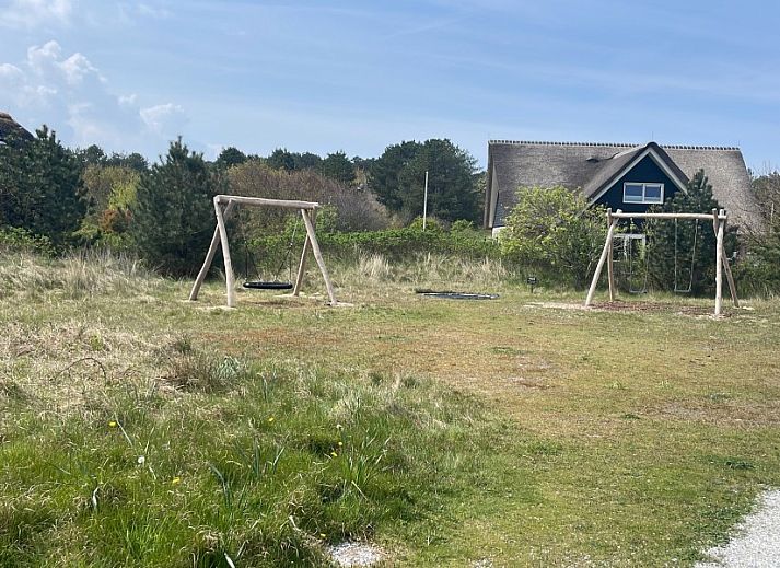 Ruim terras van Wellnessvilla Zee & Zo in Buren, Ameland omgeven door bloemen en grasland.