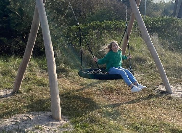 Ruim terras van Wellnessvilla Zee & Zo in Buren, Ameland omgeven door bloemen en grasland.