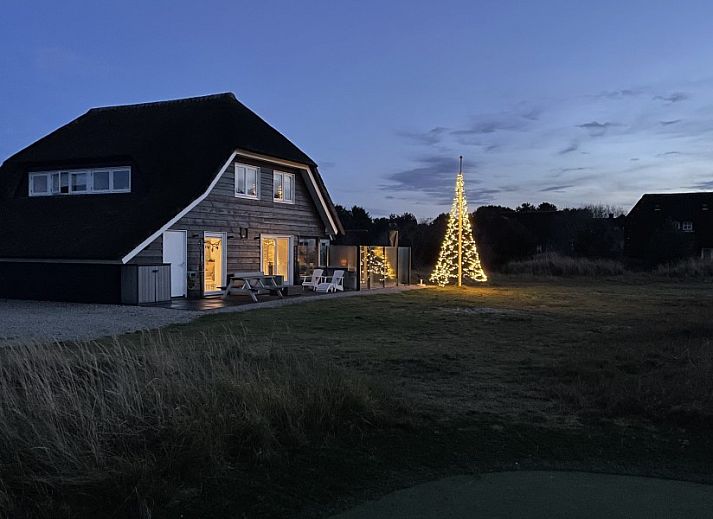 Sfeervolle binnenruimte van Wellnessvilla Zee & Zo in Buren, Ameland met open haard en grote ramen.