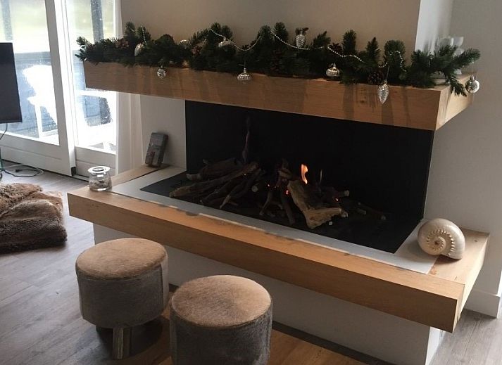 Sfeervolle binnenruimte van Wellnessvilla Zee & Zo in Buren, Ameland met open haard en grote ramen.