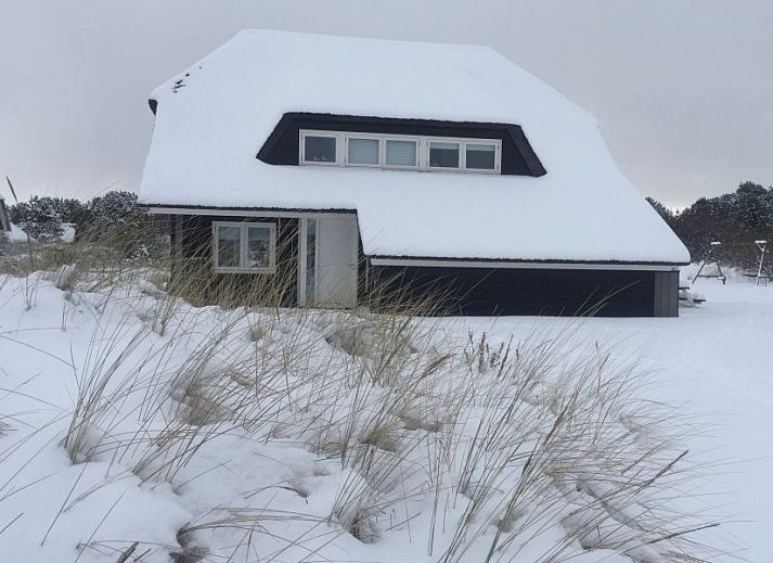 Sfeervolle binnenruimte van Wellnessvilla Zee & Zo in Buren, Ameland met open haard en grote ramen.
