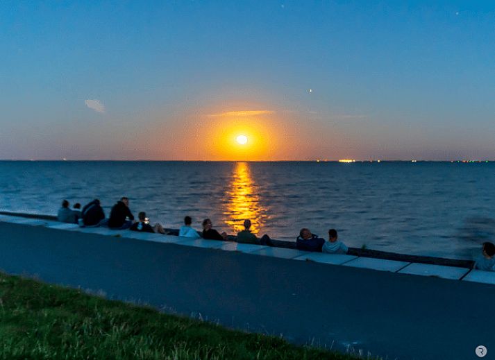 Comfortabele woonkamer in Vakantiehuisje in Buren Ameland met knusse bank en open keuken, ideaal voor ontspanning.