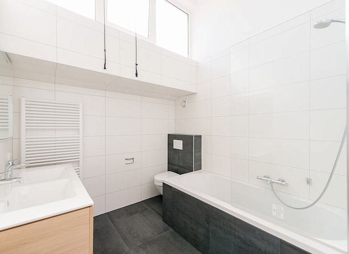 Cozy living room in Duinbungalow Luxe 10, Hollum, Ameland with comfortable seating and views of the green surroundings.