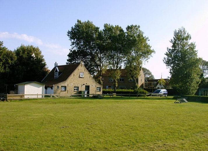 Vacation home Kiewiet Ameland in Hollum offers a charming white facade with red roof tiles, ideal for a relaxing stay on the Wadden Islands.