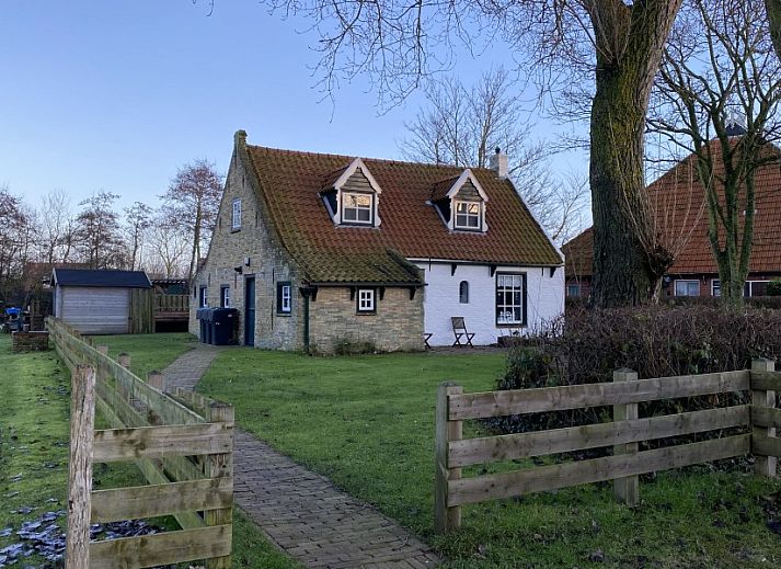 The natural setting of Holiday home Kiewiet Ameland in Hollum offers peace and privacy, surrounded by green trees and a flowering garden.
