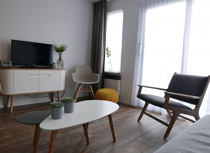 Gemuetliches Wohnzimmer in der Ferienwohnung Amelander Kaap 2, Hollum, Ameland mit bequemem Sofa und viel Tageslicht.