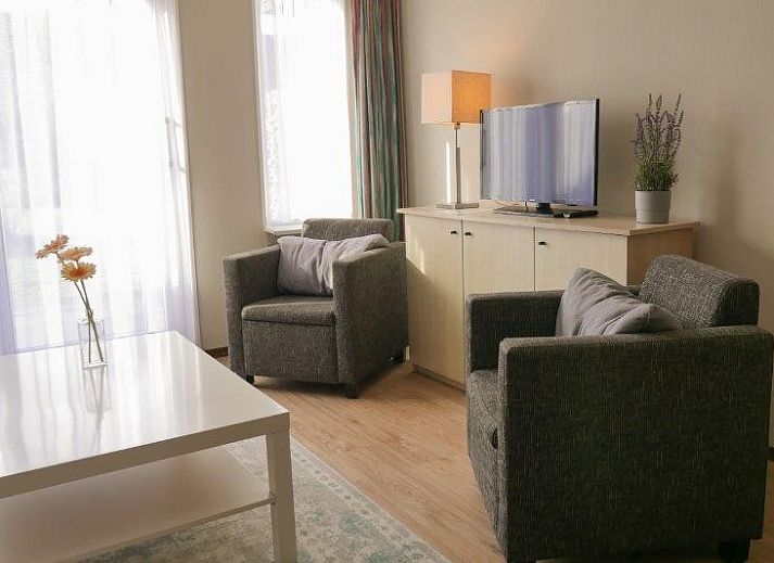 Essecke mit Holztisch und moderner Kueche in der Ferienwohnung Amelander Kaap 2, Hollum, Ameland, ideal fuer gemuetliche Mahlzeiten.