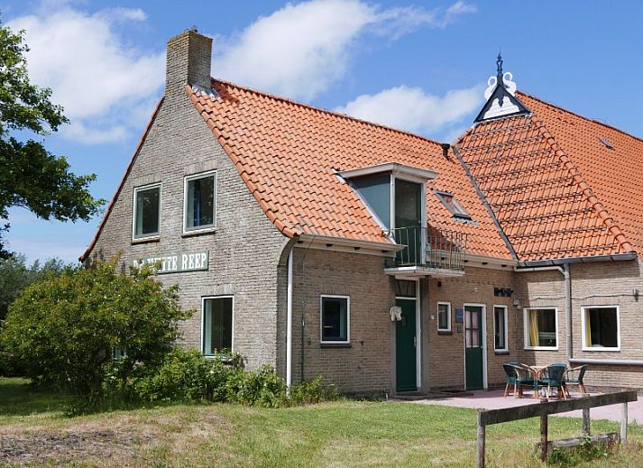 Gemuetliches Wohnzimmer in Het Woonhuis, Hollum, Ameland, mit bequemen Sofas und Blick auf die gruene Umgebung.