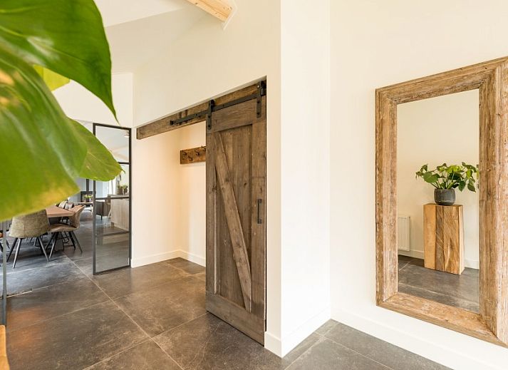 Geraeumiges Wohnzimmer im Bungalow Wagenschuur in Hollum, Ameland, mit moderner Einrichtung und Blick auf die Watteninseln.