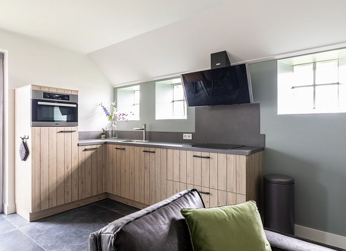 Gezellige eetruimte in De Deel, appartement in Hollum, Ameland met moderne inrichting en bloemen op tafel.