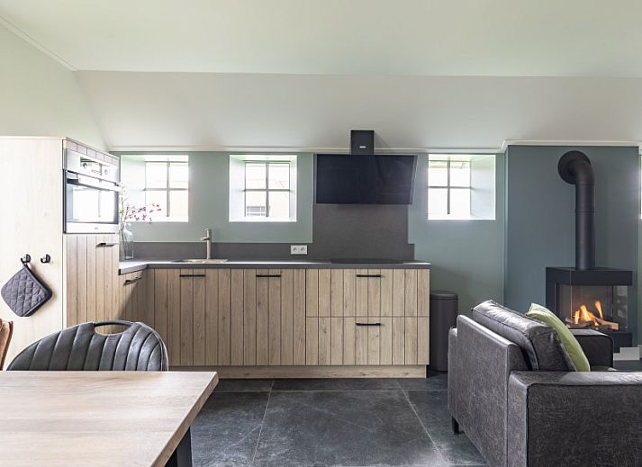 Gezellige eetruimte in De Deel, appartement in Hollum, Ameland met moderne inrichting en bloemen op tafel.