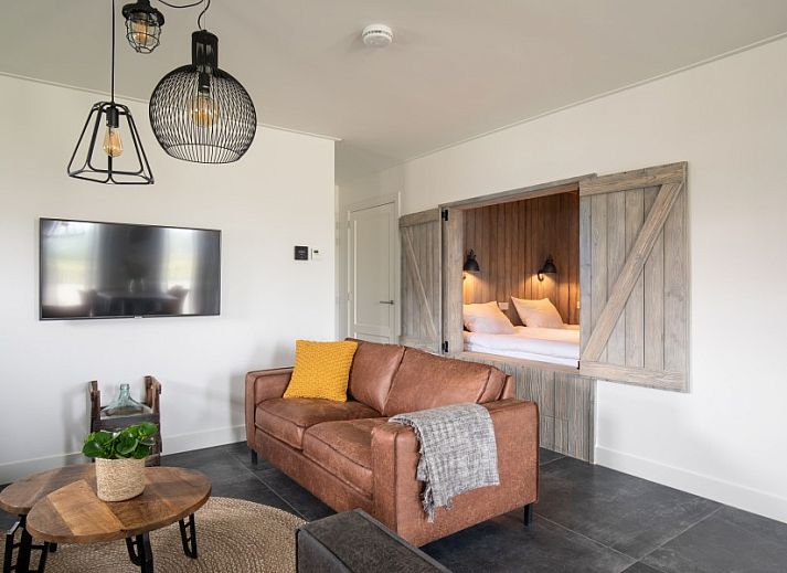 Stijlvolle eetkamer van De Deel, vakantieappartement in Hollum, Ameland, met houten tafel en designverlichting.