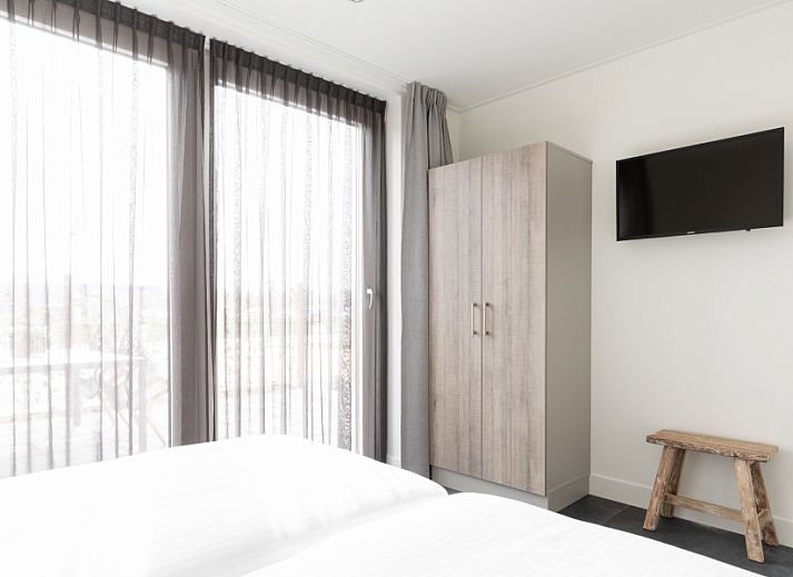 Moderne keuken in De Deel, appartement in Hollum, Ameland, met strakke houten kasten en veel lichtinval.