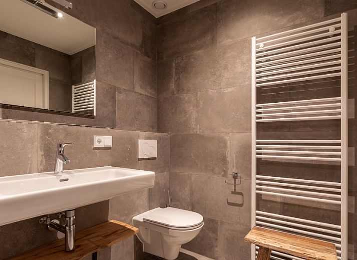 Moderne keuken in De Deel, appartement in Hollum, Ameland, met strakke houten kasten en veel lichtinval.