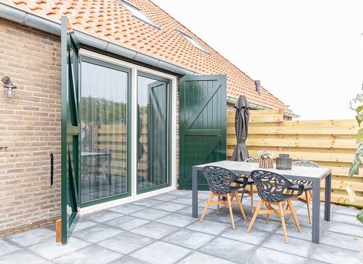 Open keuken en zithoek in De Deel, appartement in Hollum, Ameland, met sfeervolle haard en moderne voorzieningen.