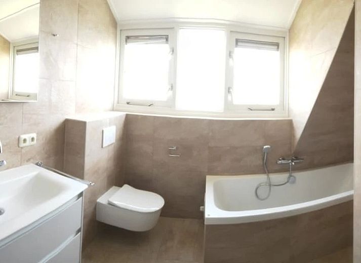 Vorderseite des Sartorius Ferienhauses in Hollum, Ameland mit grosszuegiger Auffahrt und gruener Umgebung auf den Watteninseln.