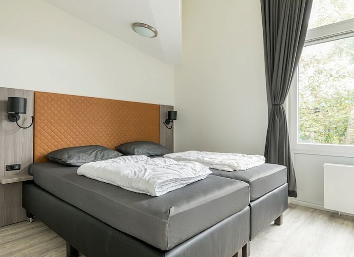 Cozy sitting area in bungalow Duyngolf 12, Hollum, Ameland with modern art and comfortable sofa, ideal for relaxing vacations on the Wadden Islands.