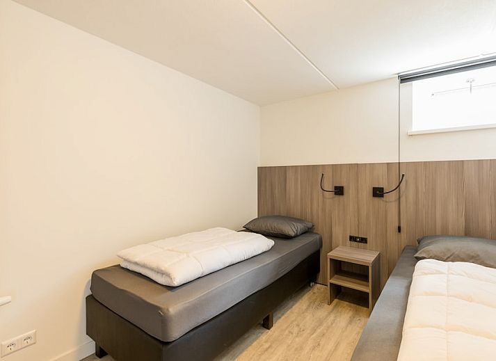 Cozy sitting area in bungalow Duyngolf 12, Hollum, Ameland with modern art and comfortable sofa, ideal for relaxing vacations on the Wadden Islands.