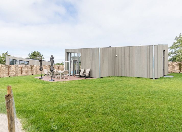 Cozy sitting area in bungalow Duyngolf 12, Hollum, Ameland with modern art and comfortable sofa, ideal for relaxing vacations on the Wadden Islands.