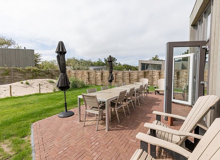Cozy sitting area in bungalow Duyngolf 12, Hollum, Ameland with modern art and comfortable sofa, ideal for relaxing vacations on the Wadden Islands.