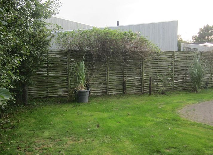 Groene tuin bij Duyngolf 71, vakantiehuis in Hollum Ameland, omringd door weelderige begroeiing.