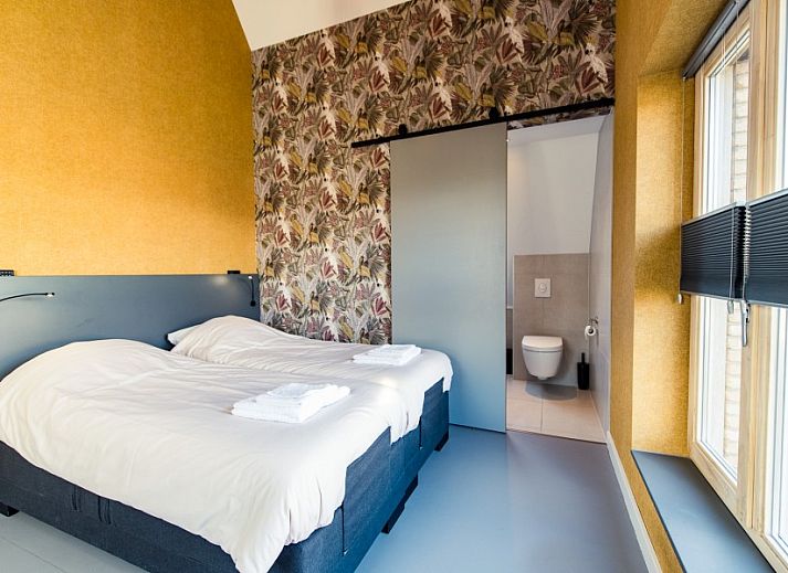 Comfortable bedroom in Breeze 2 bed and breakfast, Hollum, Ameland with double bed and colorful wallpaper.