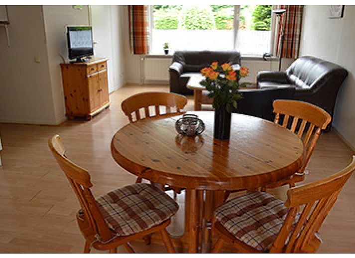 Gemuetliches Wohnzimmer in Appartementen-Annema, Nes, Ameland mit bequemer Sitzecke und Blick auf die gruene Umgebung der Watteninseln.