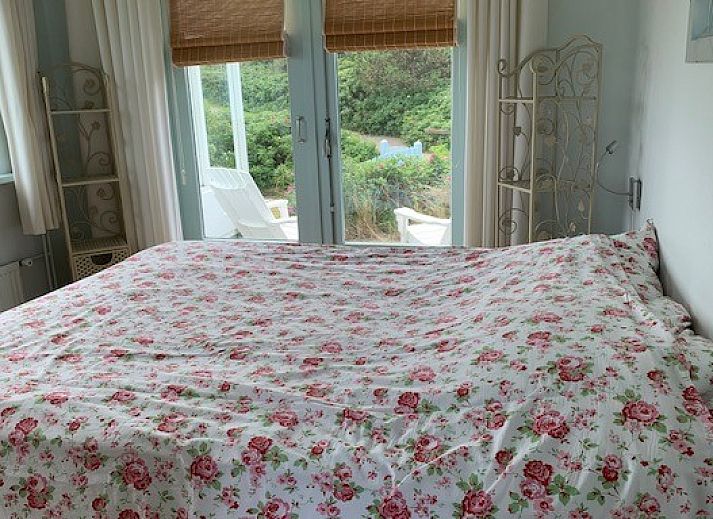 Sunny terrace of Salt bungalow in Buren, Ameland with decorative elements and parasol.