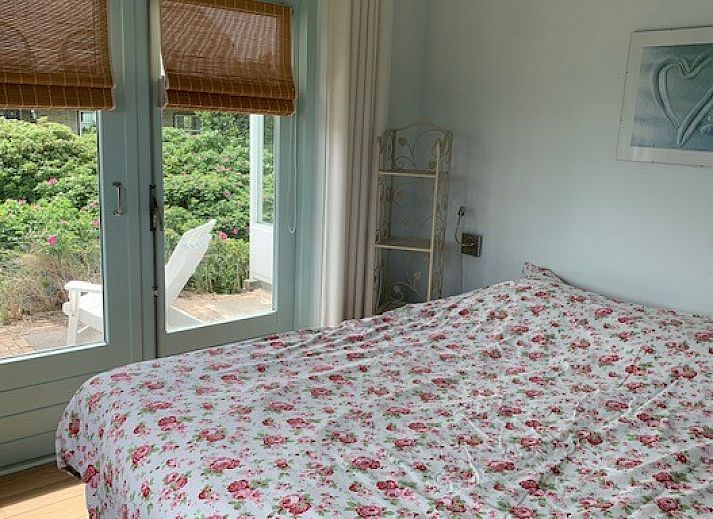 Sunny terrace of Salt bungalow in Buren, Ameland with decorative elements and parasol.