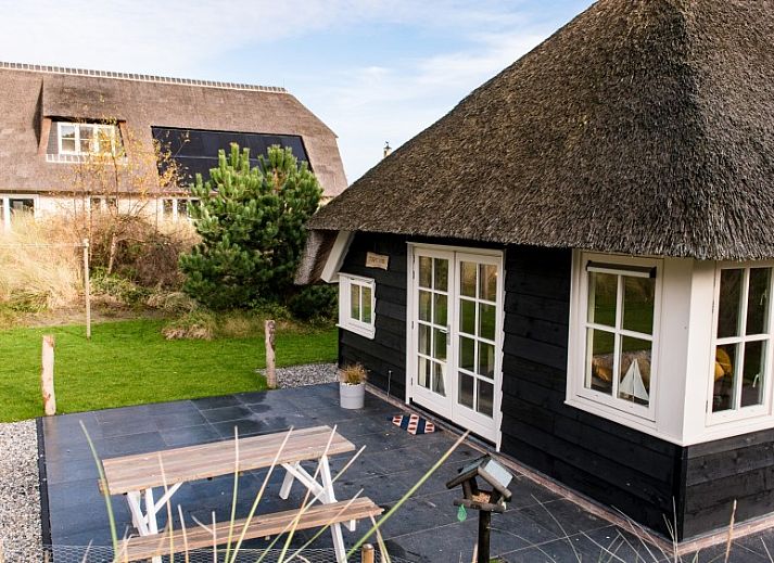 Vakantiehuis Tureluur in Buren, Ameland met rieten dak en groene tuin.