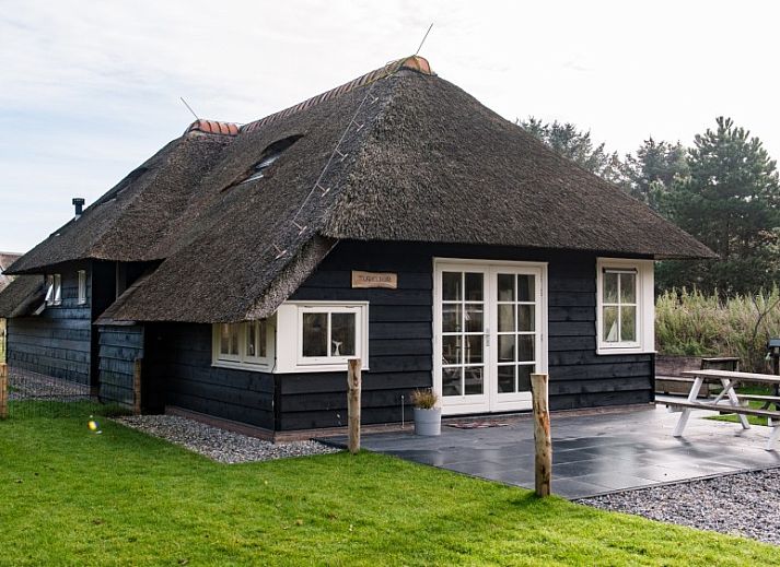 Vakantiehuis Tureluur in Buren, Ameland met rieten dak en groene tuin.