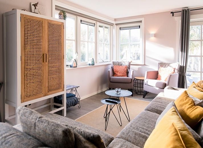 Zijaanzicht van Tureluur vakantiehuis in Buren, Ameland met houten stoelen.