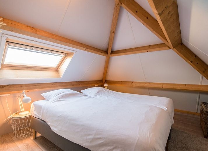 Zijaanzicht van Tureluur vakantiehuis in Buren, Ameland met houten stoelen.