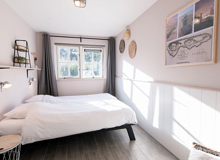 Zijaanzicht van Tureluur vakantiehuis in Buren, Ameland met houten stoelen.