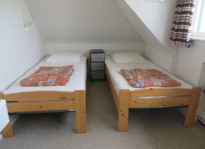 Gemuetliches Wohnzimmer des Ferienhauses Zeerust auf Schiermonnikoog, mit Korbmoebeln und Blick auf die Natur des Wattenmeeres.