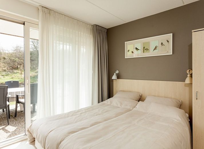 Zonnig terras van Villa Rietberg op Schiermonnikoog, vakantiehuis met buitenzitje en natuur.